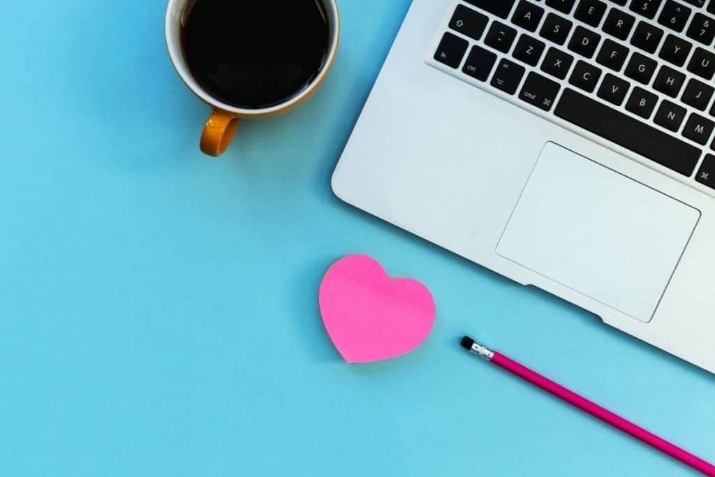 Heart-shaped notepad and coffee sitting at a business woman's desk