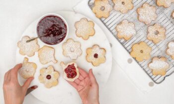 Overhead view of a woman's hands, decorating shortbread cookies.