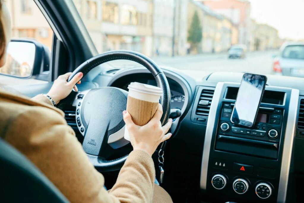 A woman driving a car, using a smartphone for navigation.