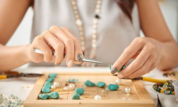 Close up of a woman at a desk, using tools to create handmade jewelry for Etsy.