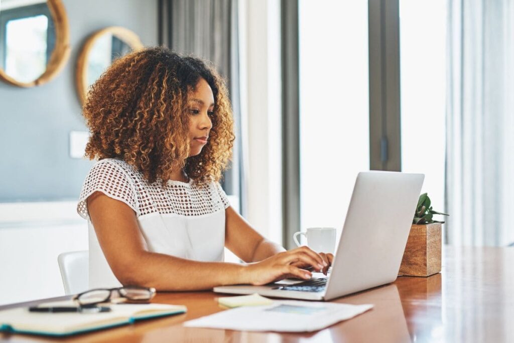 Woman looking for work on laptop in home office.