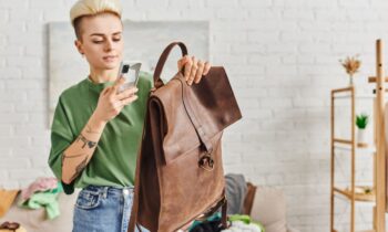 Woman using a phone to take a picture of a used leather bag for selling online.