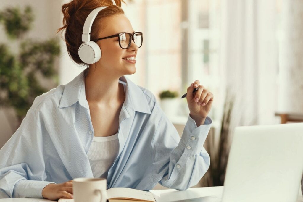 A work from home captioner wearing headphones and working on a computer.