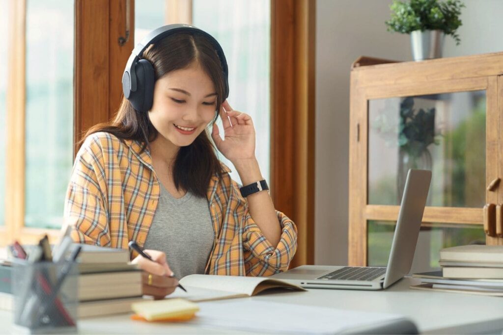 13 Easy Side Hustles for College Students to Earn Extra Cash 4 A college student working from home, taking notes in a notebook.