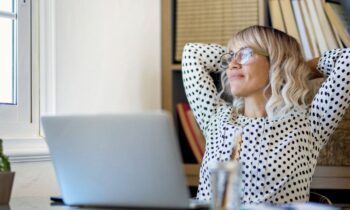 A happy, smiling business woman sitting in her home office, looking at the window.