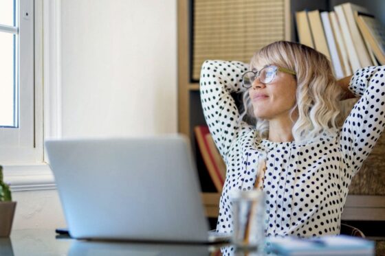 A happy, smiling business woman sitting in her home office, looking at the window.