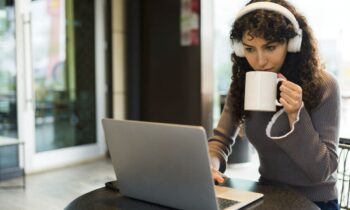 A woman working quietly in a cafe, using a laptop and drinking coffee for blog post Remote Jobs That Don't Require Talking