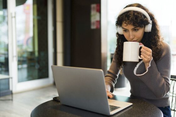 A woman working quietly in a cafe, using a laptop and drinking coffee for blog post Remote Jobs That Don't Require Talking