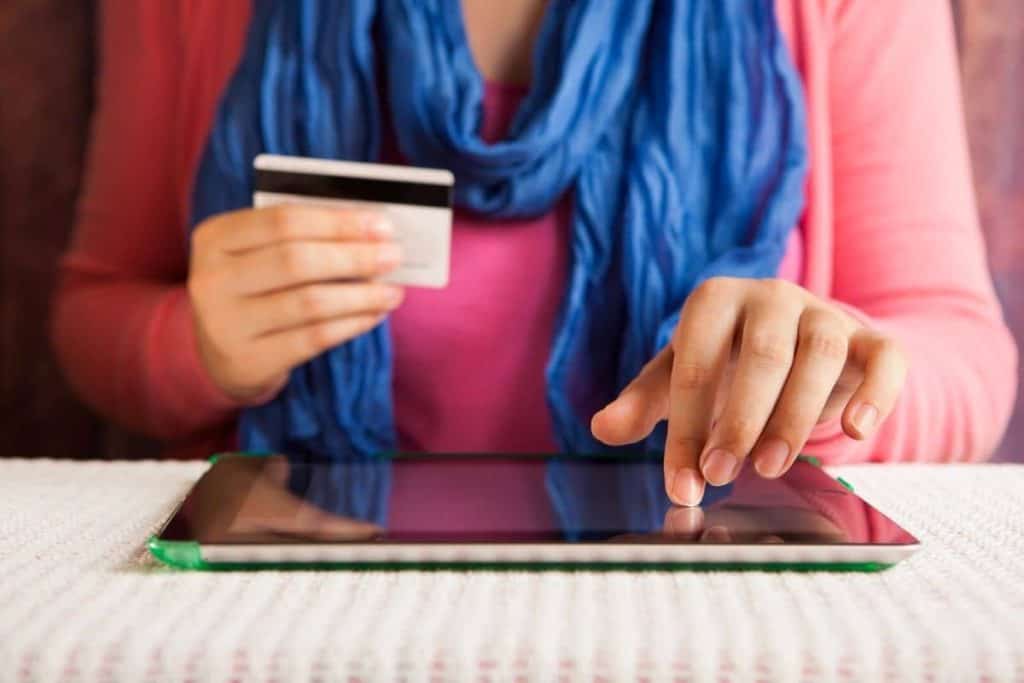 Closeup image of a woman using and iPad and shopping online while holding a giftcard.