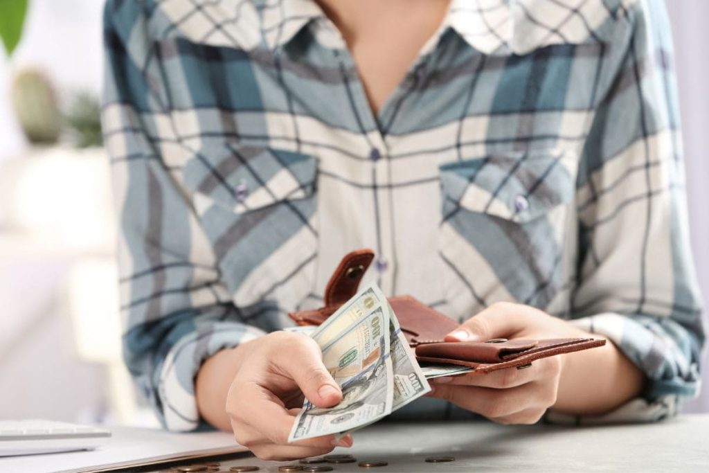 A woman holding an open wallet and cash.
