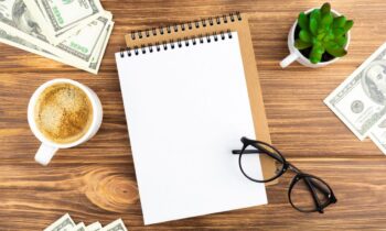 A remote worker's desk, with a notebook, cash, and coffee for blog post make more money