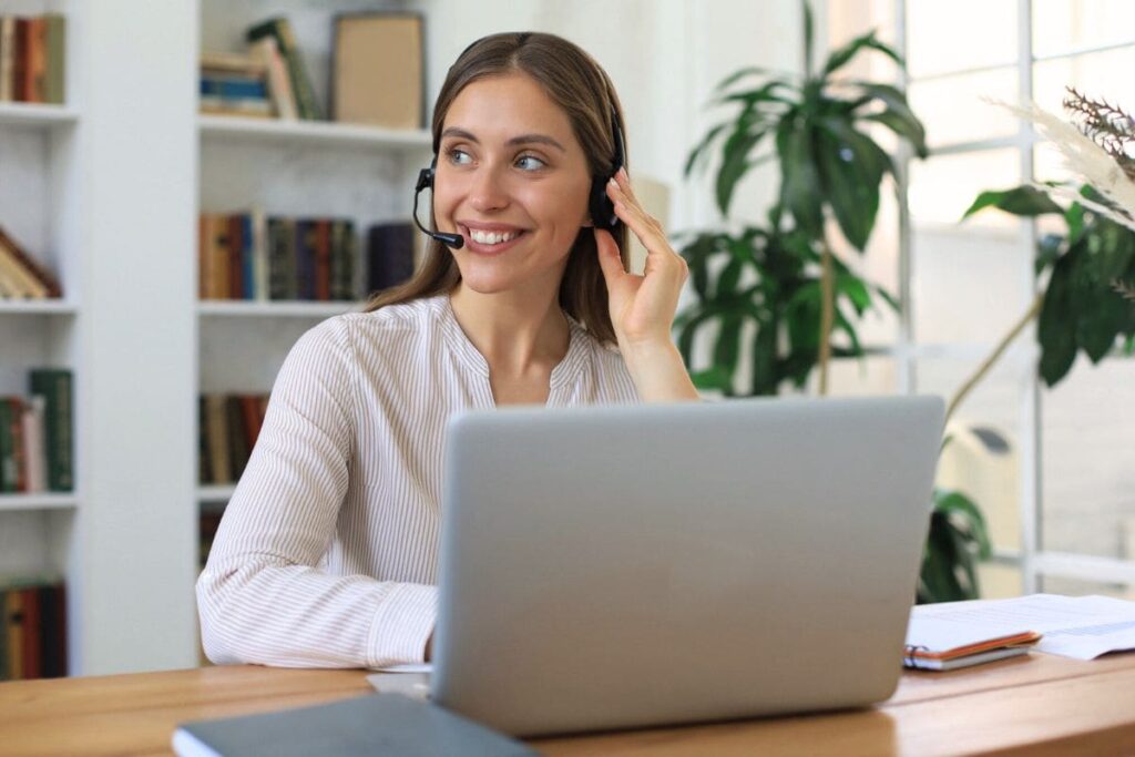 A remote dispatcher working from her home office on a laptop and using a headset.