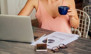 A woman working from home and drinking coffee at her computer.