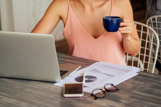A woman working from home and drinking coffee at her computer.