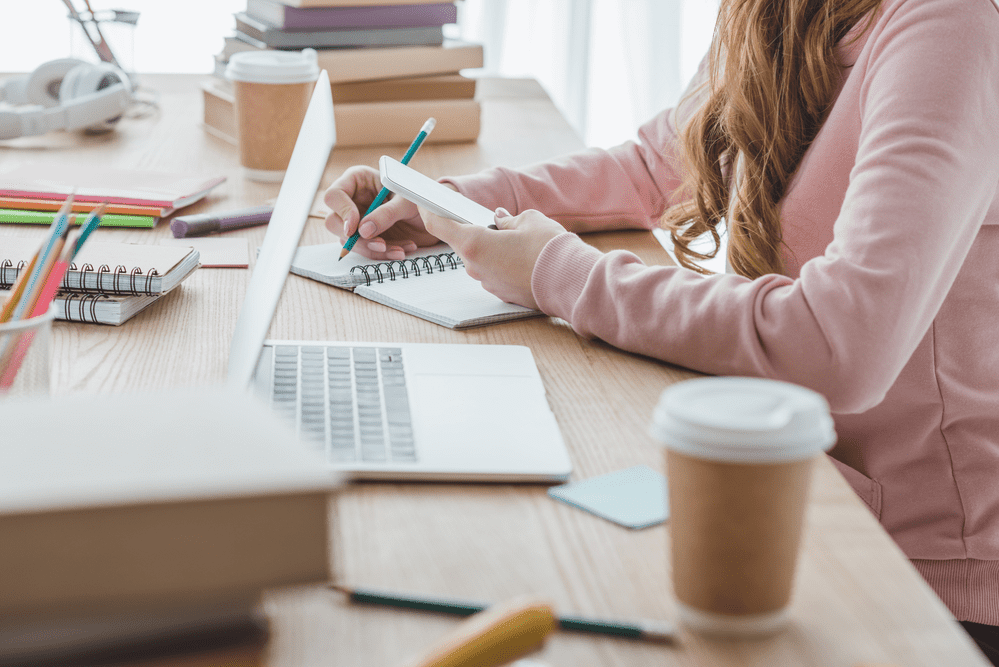 Young woman studying at desk and drinking coffee