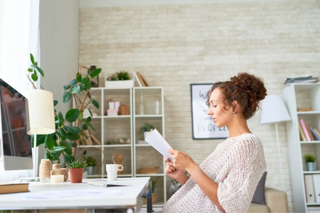 A woman business owner, sitting at a desk, reading a book.
