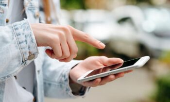 A gig worker walking on the street, using her phone.
