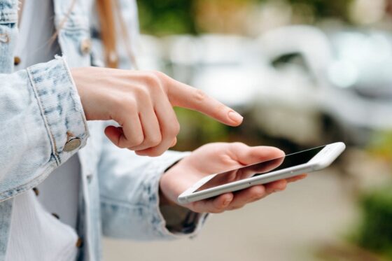 A gig worker walking on the street, using her phone.