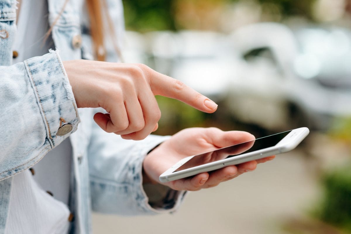 A gig worker walking on the street, using her phone.