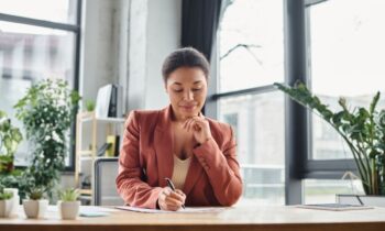 A remote human resources professional working from home office and writing in a notebook.