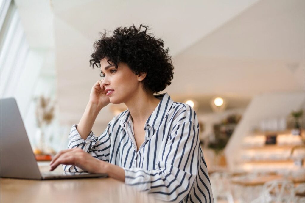 A woman working remotely from home, using a laptop and talking on the phone.