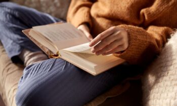 A woman sitting on a couch, reading a book.