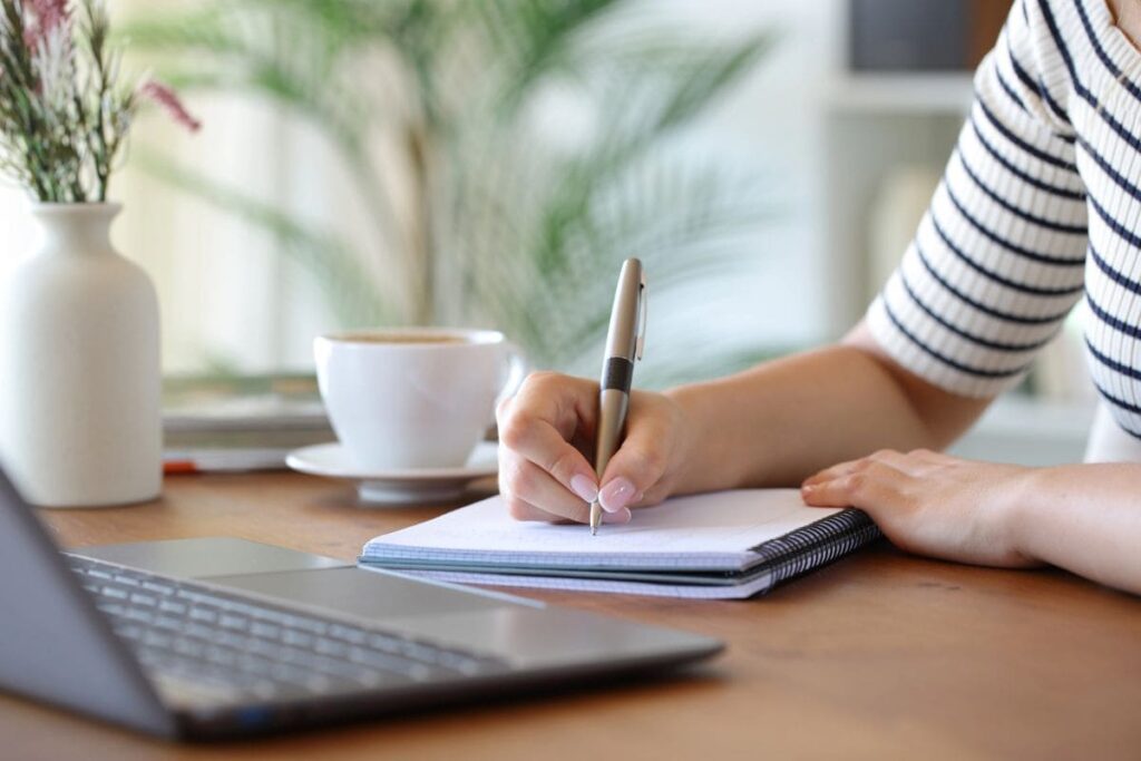 A woman sitting at a desk, writing notes on a clipboard.