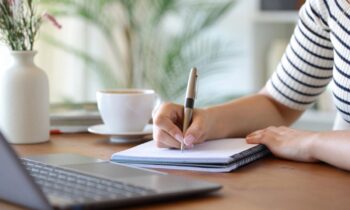 A woman sitting at a desk, writing notes on a clipboard for blog post LinkedIn job search strategies