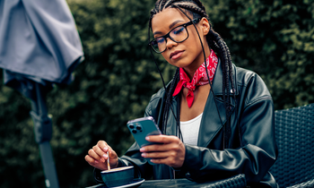 A stylish young woman with braided hair enjoying coffee outdoors and using money-making apps