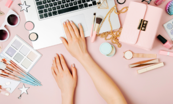 A woman on her computer with makeup surrounding her looking for a list of direct sales companies