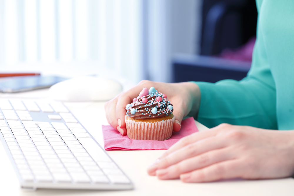 A woman sitting at her desk getting ready to eat her free birthday cupcake