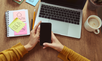A woman sitting at her desk looking at her phone for low-cost franchises from home