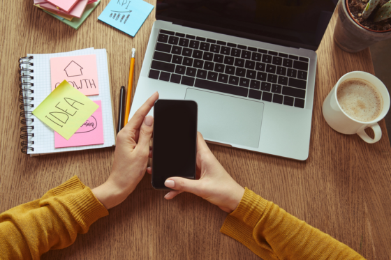 A woman sitting at her desk looking at her phone for low-cost franchises from home