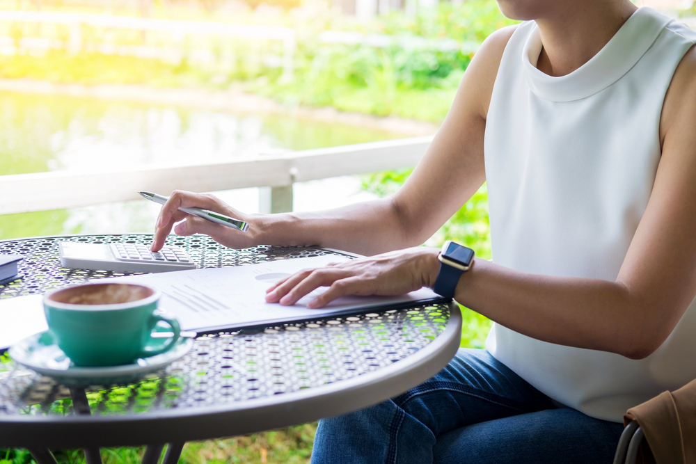 A woman sitting outdoors adding to-dos to her notebook for blog post running errands for money