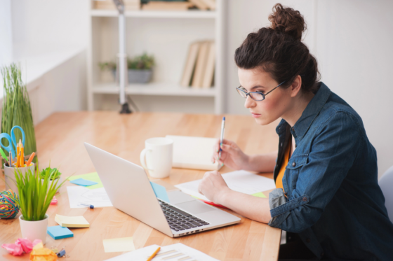A woman wearing a denim shirt looking at her laptop for a virtual part-time job
