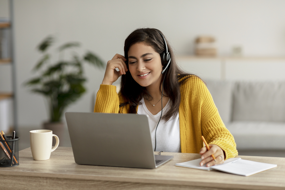 A woman wearing a sweater and headset works at Arolica's job