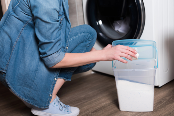 A woman wearing blue jeans working from home getting paid to do laundry
