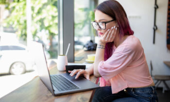 A woman wearing glasses reading a CrowdGen by Appen review on her laptop