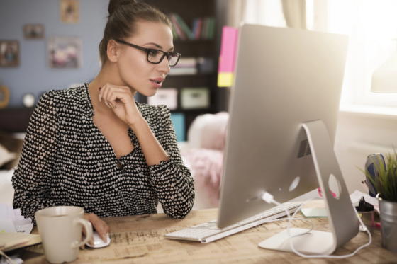 A woman wearing glasses working on her computer searching for a W-2 work from home job