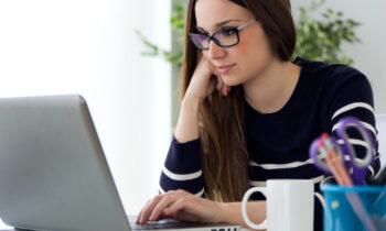 A woman with long brown hair wearing glasses participating in a paid focus group online