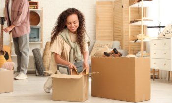 A woman with long curly hair boxing items up to sell at a garage sale for blog post things to sell