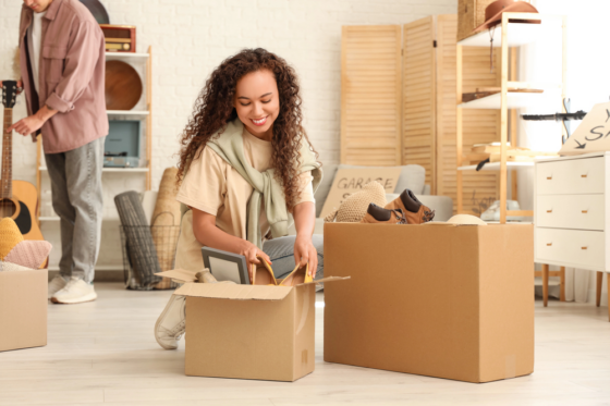 A woman with long curly hair boxing items up to sell at a garage sale for blog post things to sell