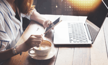 A woman with red hair in a cafe with her laptop looking for flexible work from home jobs