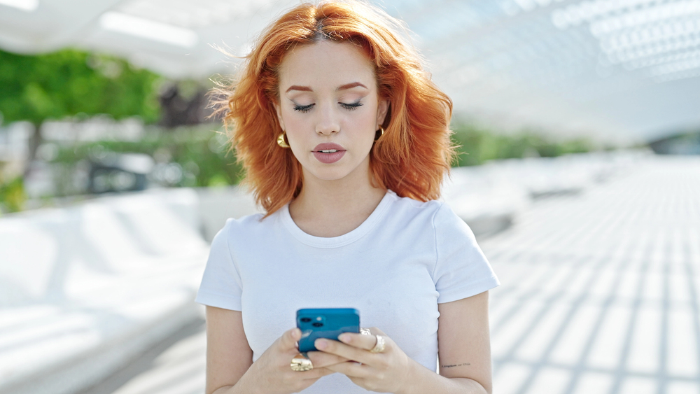 A woman with red hair making money online watching videos on her phone