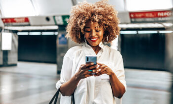 A young woman in the subway looking at her phone completing tasks on InboxDollars