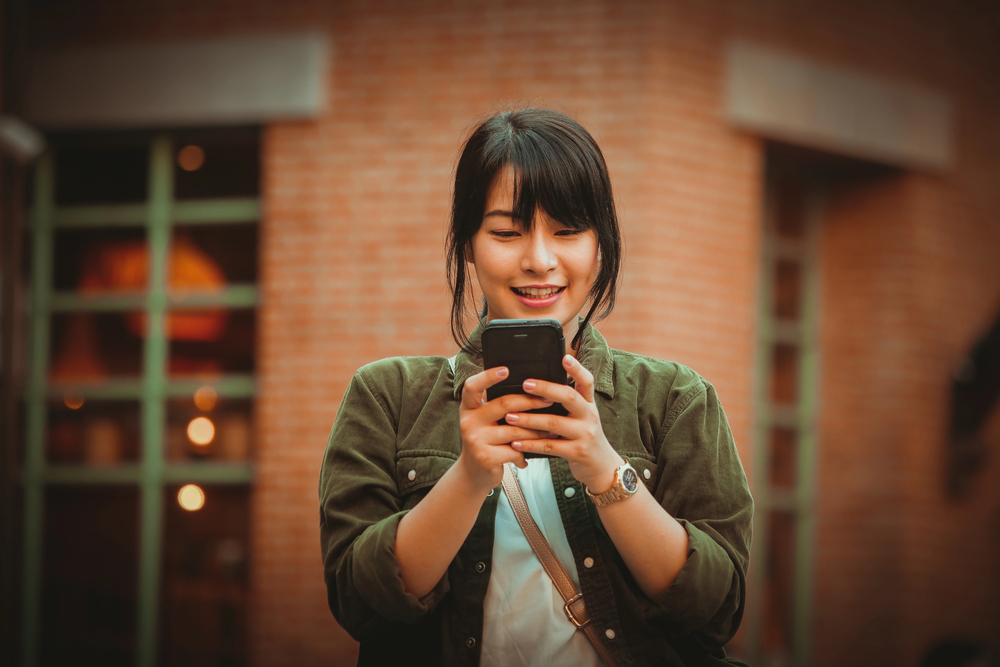 A young woman looking at her mobile device learning about mobile phone jobs