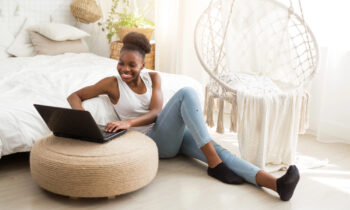 A young woman sitting on the floor working on her laptop looking for virtual jobs online