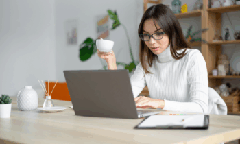 A young woman with glasses drinking coffee prepping for her data entry job