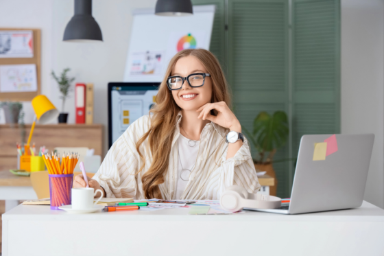 A young woman with long hair and glasses working on her laptop at home for fun work from home jobs
