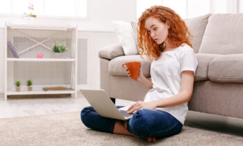 A young woman with long wavy red hair reading a MyPoints review on her laptop